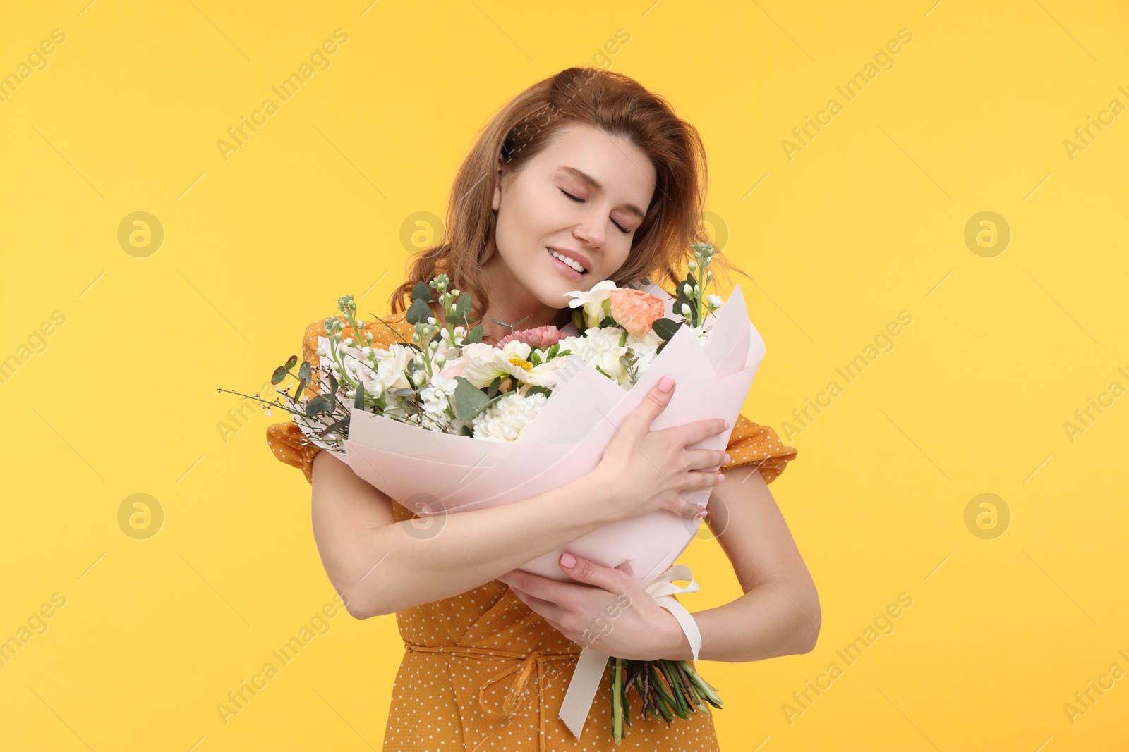 Photo of Happy woman with bouquet of beautiful flowers on yellow background