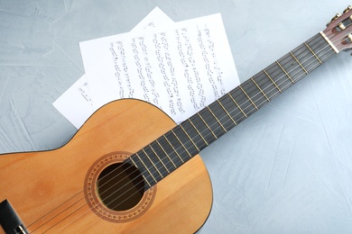 Photo of Beautiful classical guitar and music sheets on color background, top view