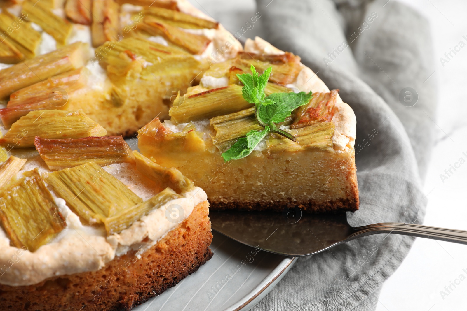 Photo of Freshly baked rhubarb pie and spatula on white table, closeup