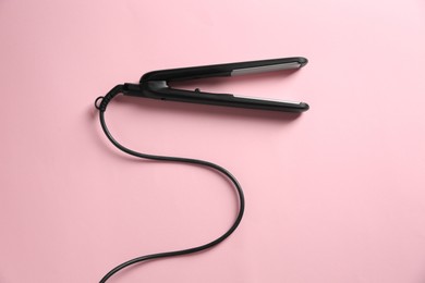 Modern flat hair iron on pink background, top view