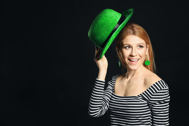 Young woman with green hat on black background, space for text. St. Patrick's Day celebration