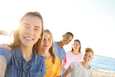 Photo of Group of children taking selfie on beach. Summer camp