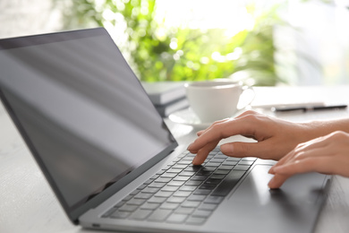 Photo of Woman working with modern laptop at white wooden table, closeup
