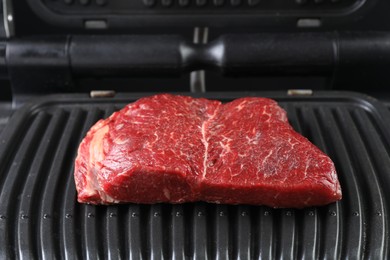 Photo of Cooking fresh beef cut on electric grill, closeup