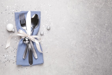 Photo of Cutlery set on grey table, top view with space for text. Christmas celebration