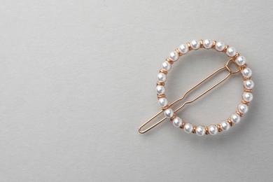 Photo of Elegant pearl hair clip on white background, top view. Space for text