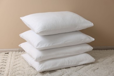 Photo of Stack of soft white pillows near beige wall indoors