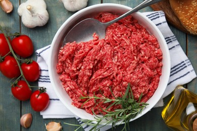 Fresh minced meat and other ingredients on light blue wooden table, flat lay