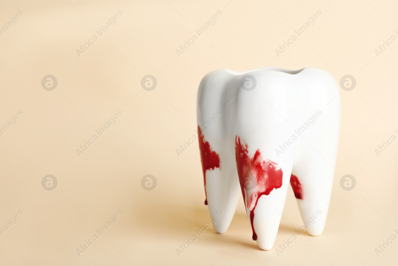 Photo of Tooth model with blood in toothpaste foam on beige background, space for text. Gum problems