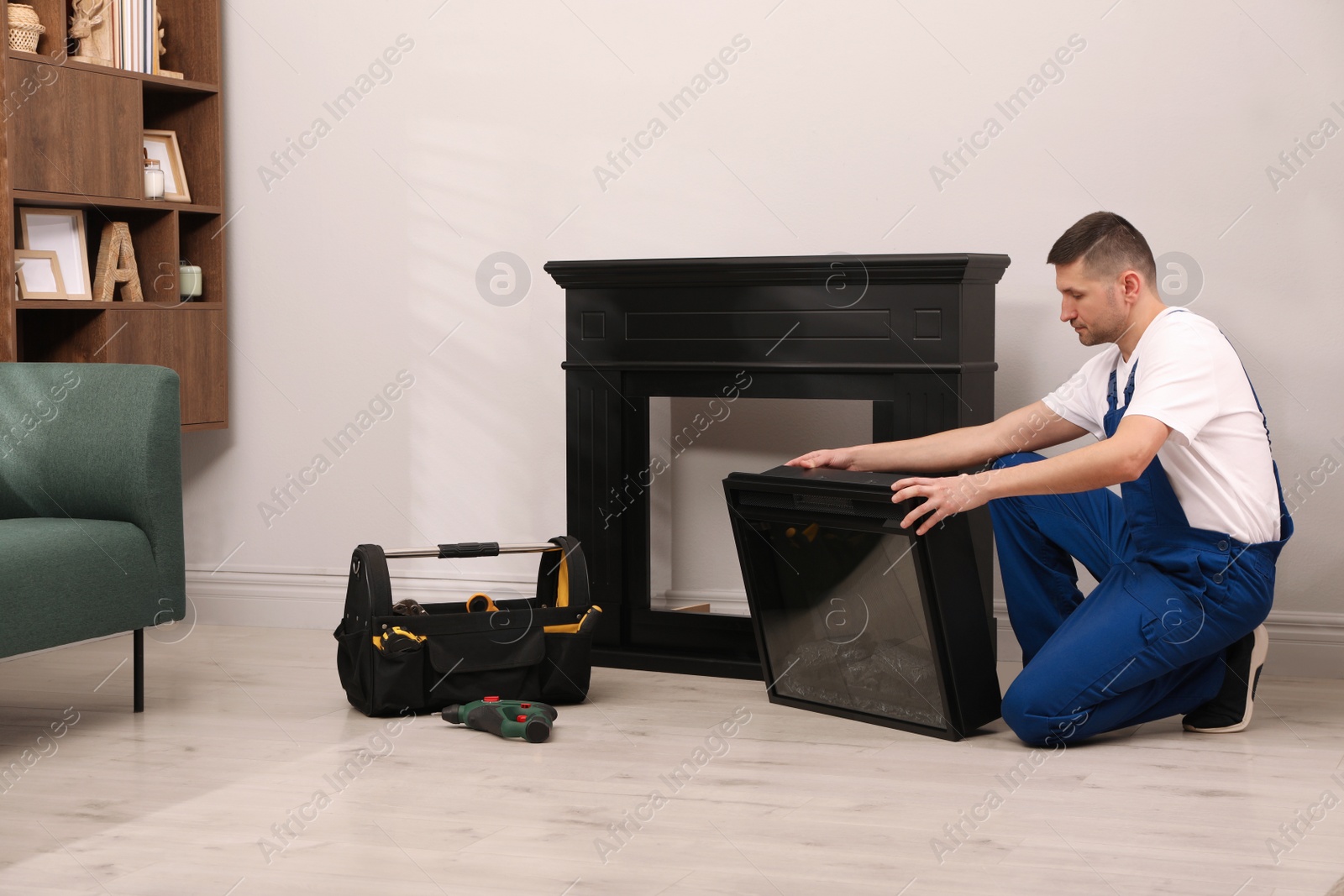 Photo of Professional technician installing electric fireplace in room