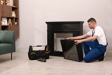 Professional technician installing electric fireplace in room