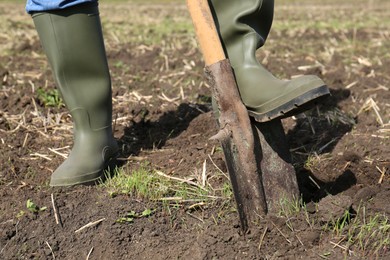Photo of Man digging soil with shovel in field, closeup