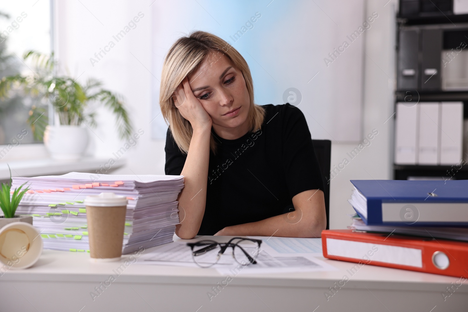 Photo of Overwhelmed woman sitting at table in office