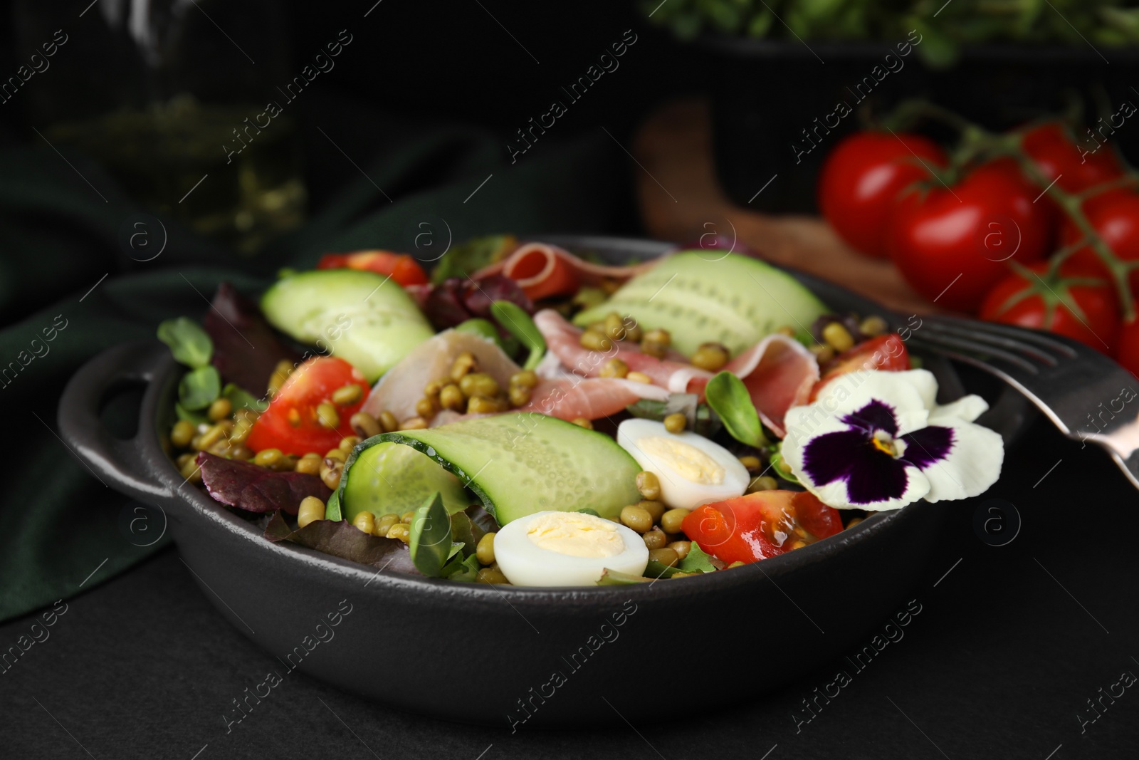 Photo of Bowl of salad with mung beans on black table, closeup