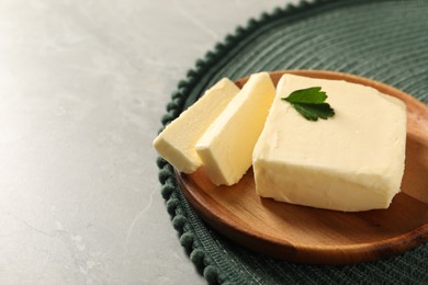 Photo of Cut tasty butter with parsley on grey table. Space for text