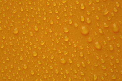 Water drops on orange background, top view