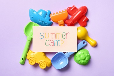 Photo of Card with text SUMMER CAMP and different sand molds on color background, flat lay