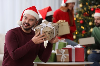 Christmas celebration in circle of friends. Happy man with gift box at home, selective focus