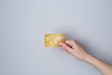 Woman holding credit card on light grey background, closeup