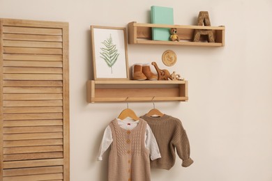 Children's room interior with stylish wooden furniture, baby clothes and decor elements