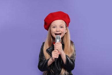 Photo of Cute little girl with microphone singing on purple background