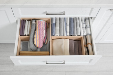 Photo of Open drawer with different textiles in kitchen, above view