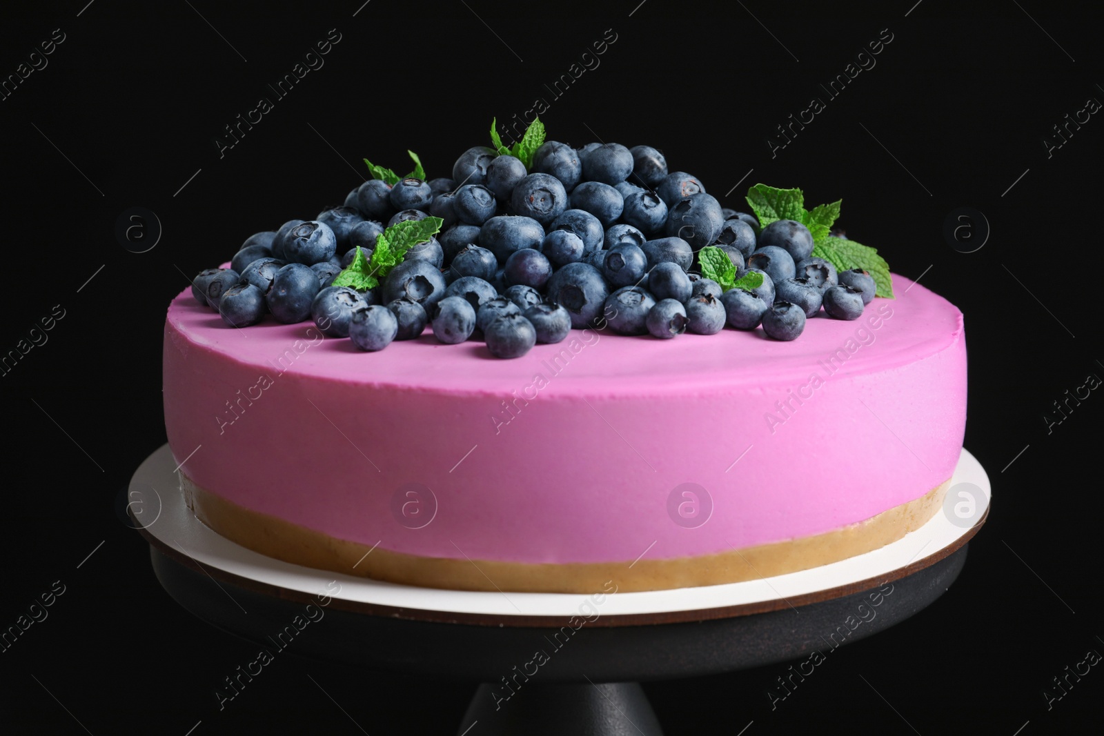 Photo of Stand with tasty blueberry cake on black background