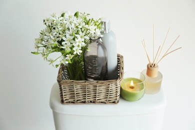 Decor elements on toilet tank near white wall. Bathroom interior