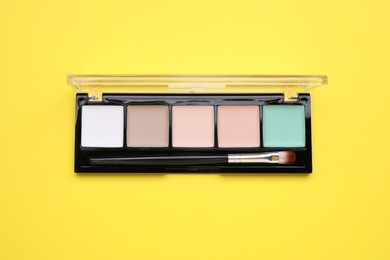 Photo of Contouring palette on yellow background, top view. Professional cosmetic product