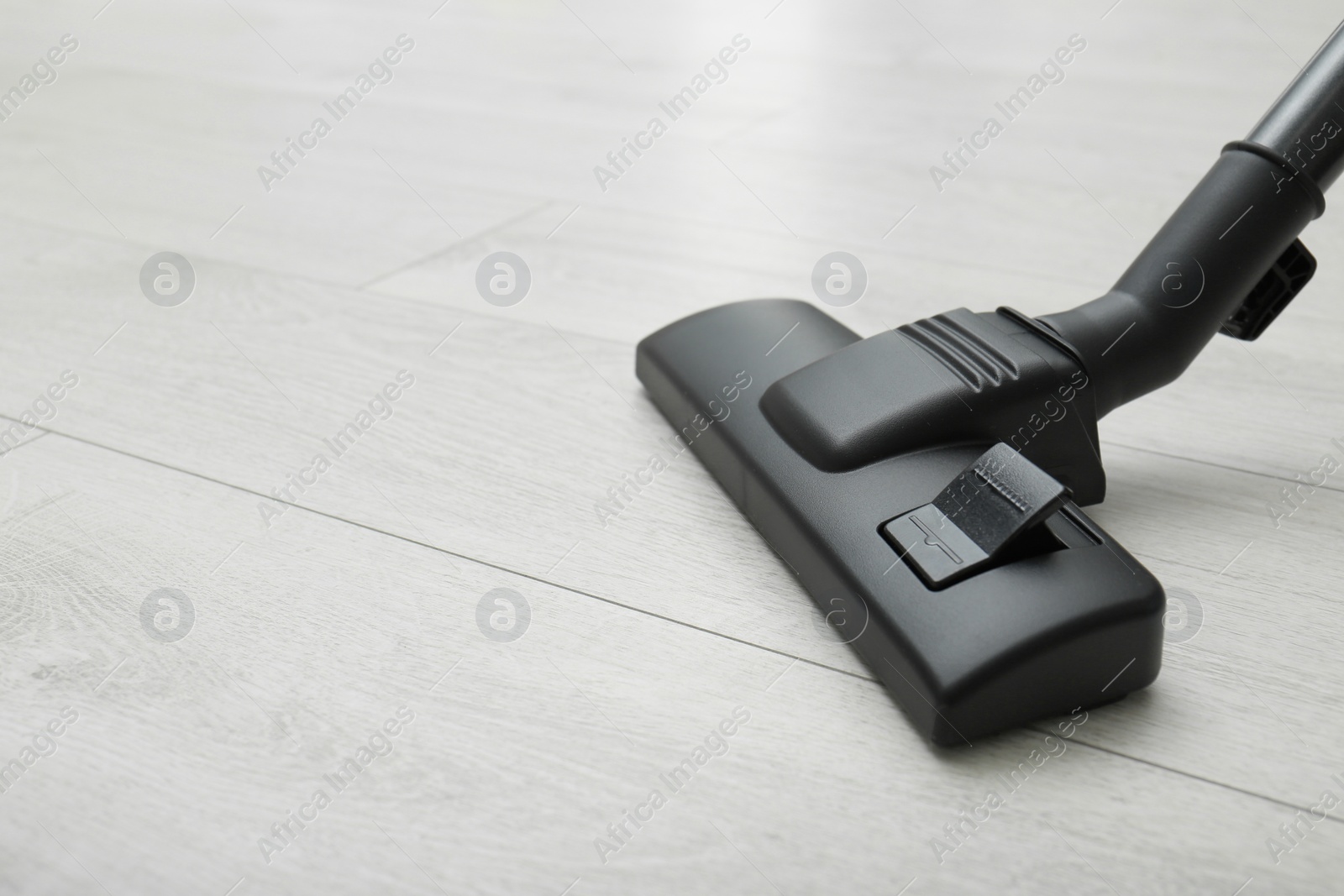 Photo of Hoovering floor with modern vacuum cleaner. Space for text