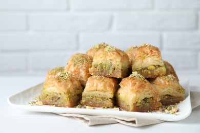 Photo of Delicious fresh baklava with chopped nuts on white table, closeup. Eastern sweets