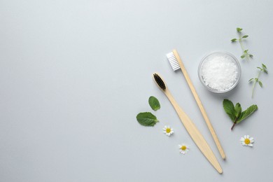 Photo of Bamboo toothbrushes, beautiful chamomile flowers, sea salt and herbs on white background, flat lay. Space for text
