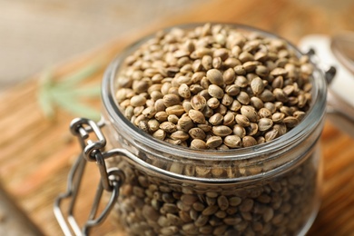Photo of Organic hemp seeds in jar on table, closeup