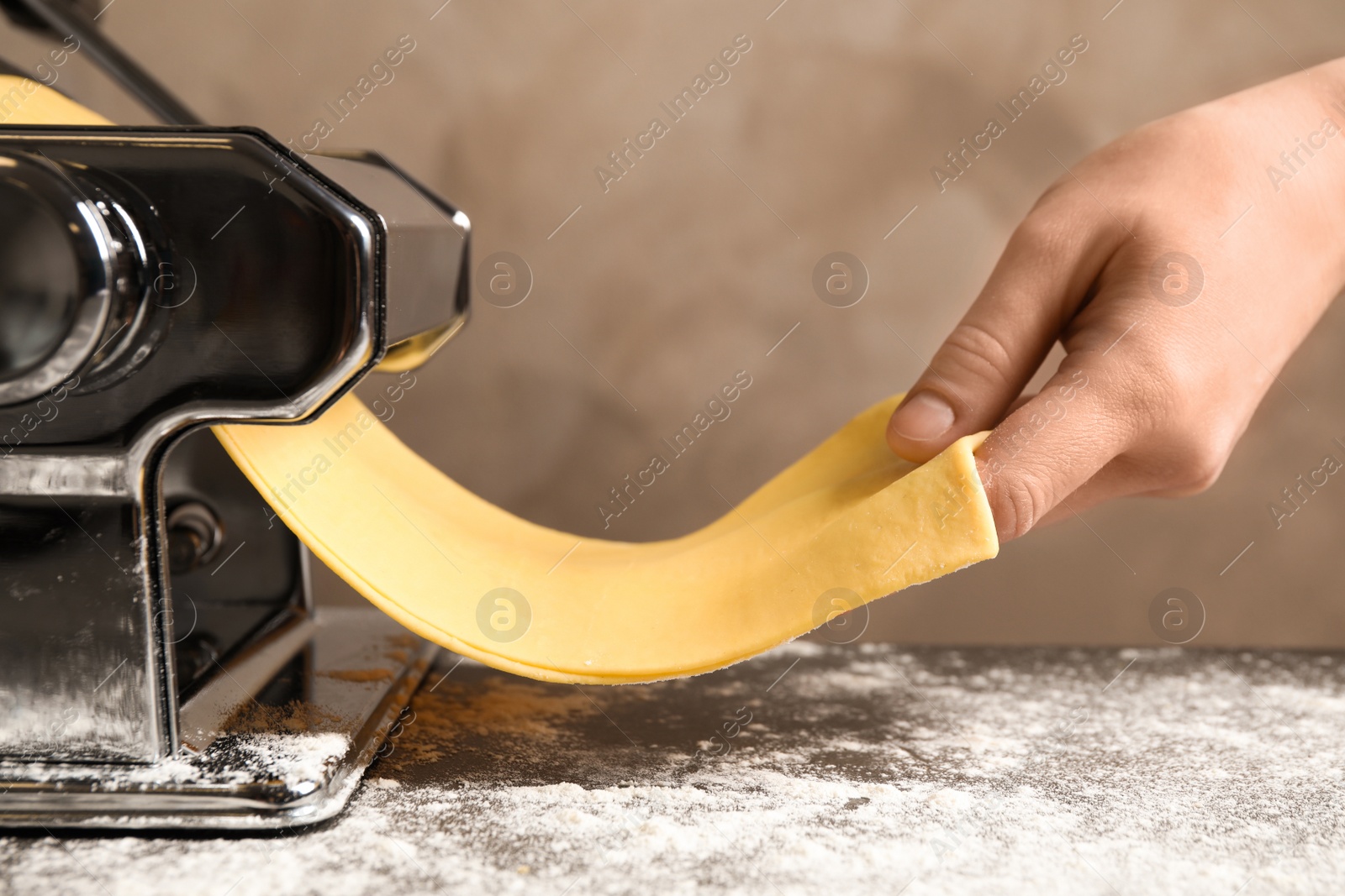 Photo of Woman preparing dough with pasta maker machine at table, closeup