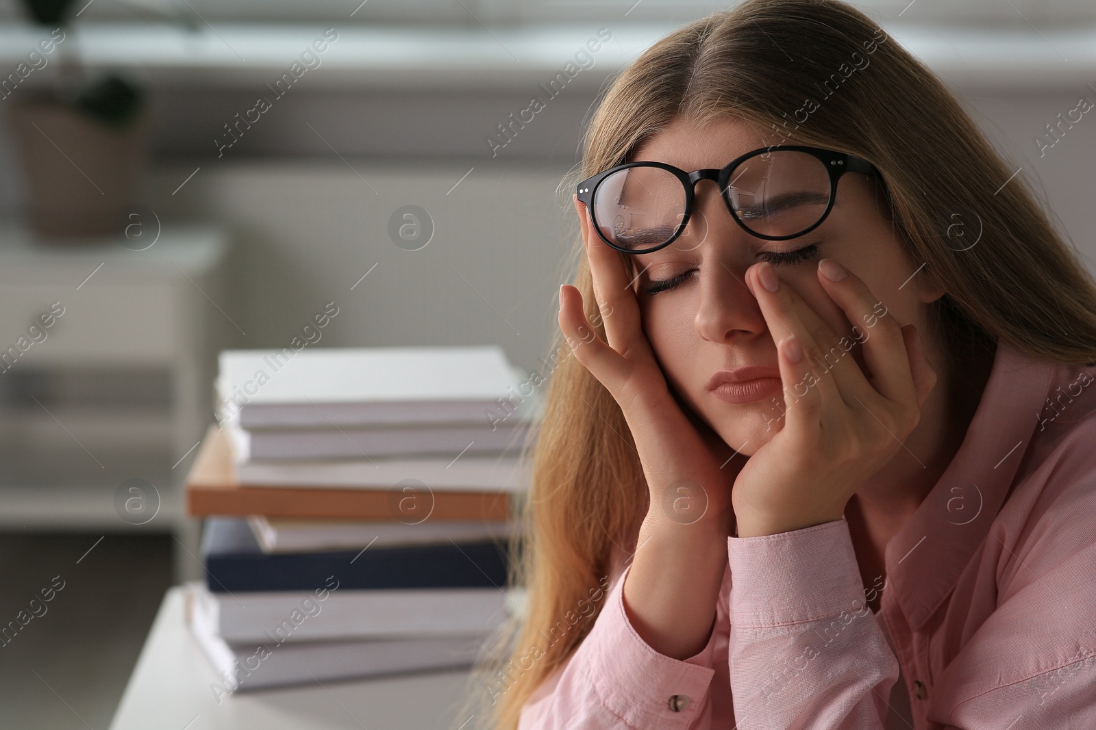 Photo of Young tired woman studying at white table indoors. Space for text