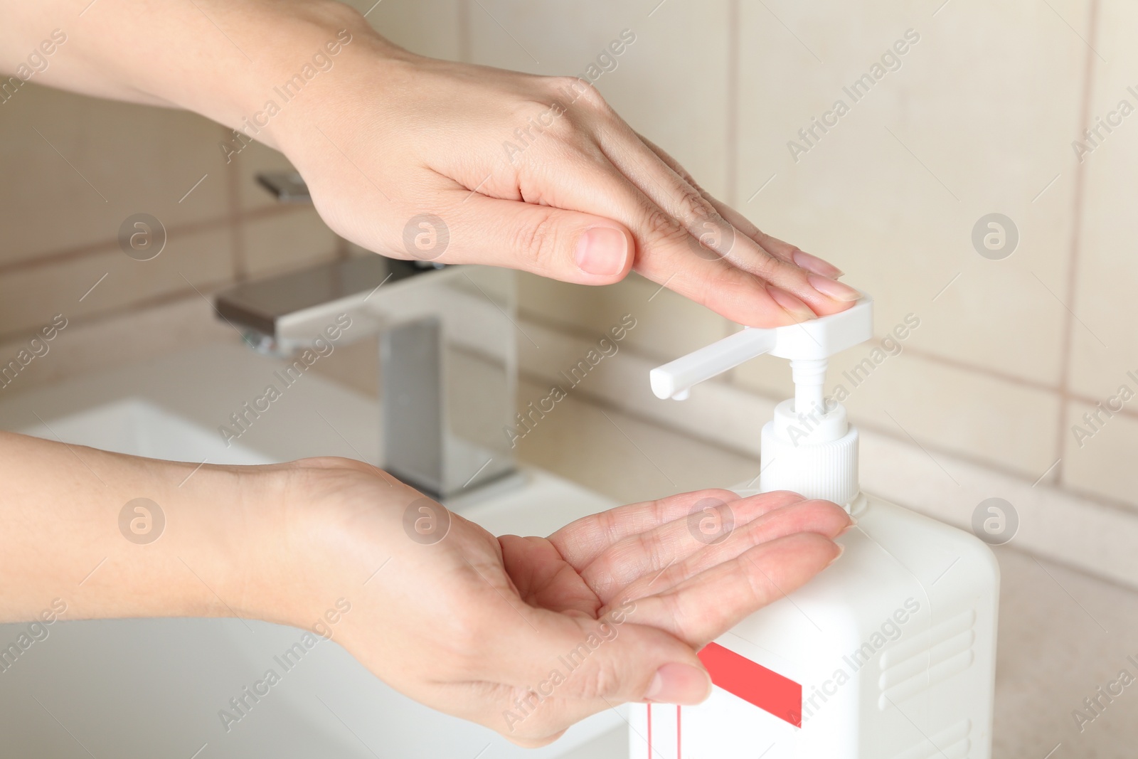 Photo of Woman applying antiseptic gel on hand in public bathroom, closeup