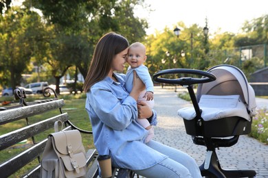 Young mother with her baby on bench in park