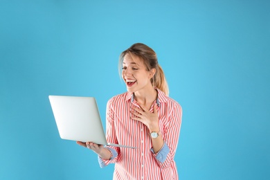 Portrait of excited young woman in casual outfit with laptop on color background