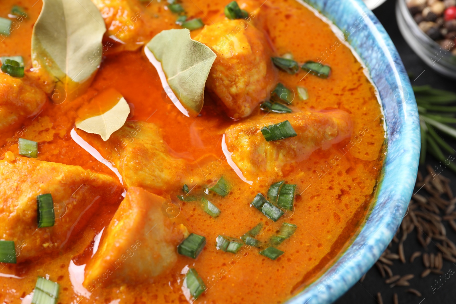 Photo of Bowl of delicious chicken curry on table, closeup