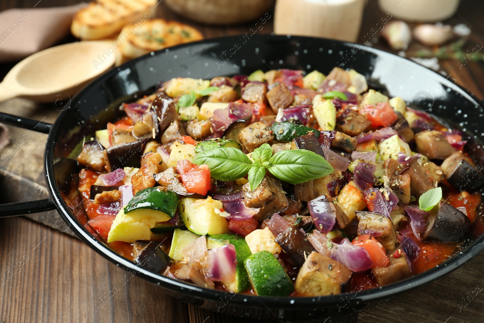 Photo of Delicious ratatouille in baking dish on wooden table, closeup