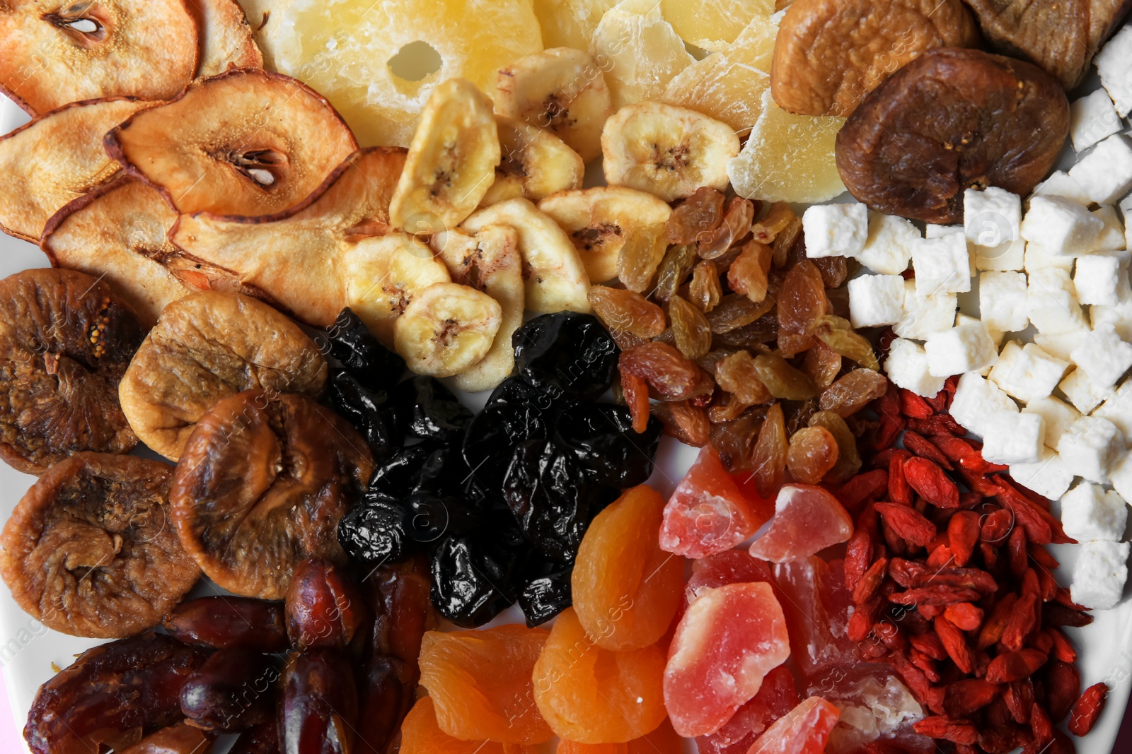 Photo of Different dried fruits on plate, top view