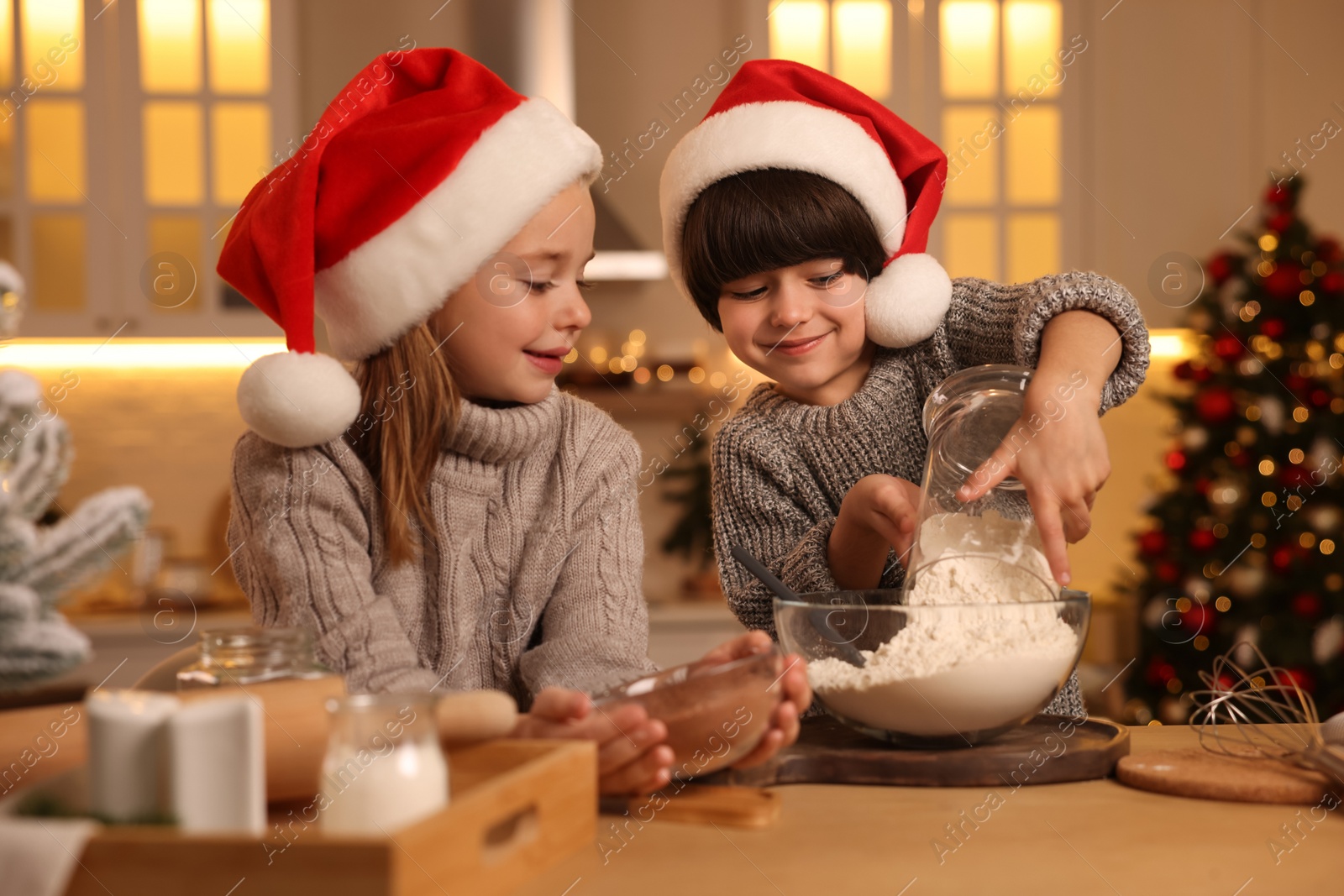 Photo of Cute little children making dough for Christmas cookies in kitchen