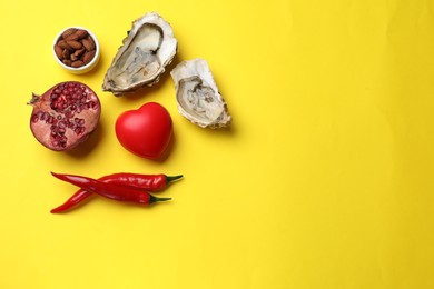 Photo of Natural aphrodisiac. Different food products and red decorative heart on yellow background, flat lay. Space for text