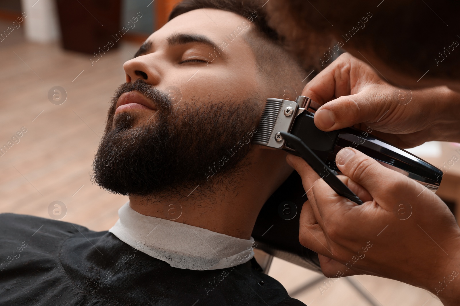 Photo of Professional hairdresser working with client in barbershop, closeup