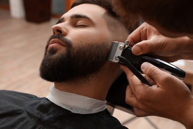 Professional hairdresser working with client in barbershop, closeup