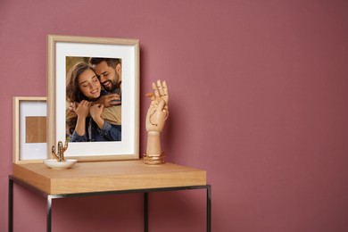 Portrait of happy young couple in photo frame on table near color wall