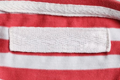 Photo of Empty clothing label on striped garment, top view