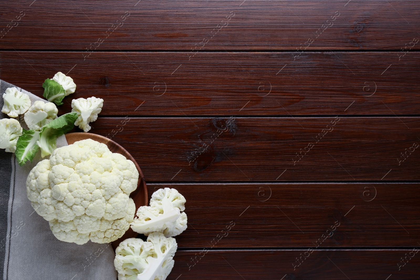 Photo of Plate with fresh raw cauliflower on wooden table, flat lay. Space for text