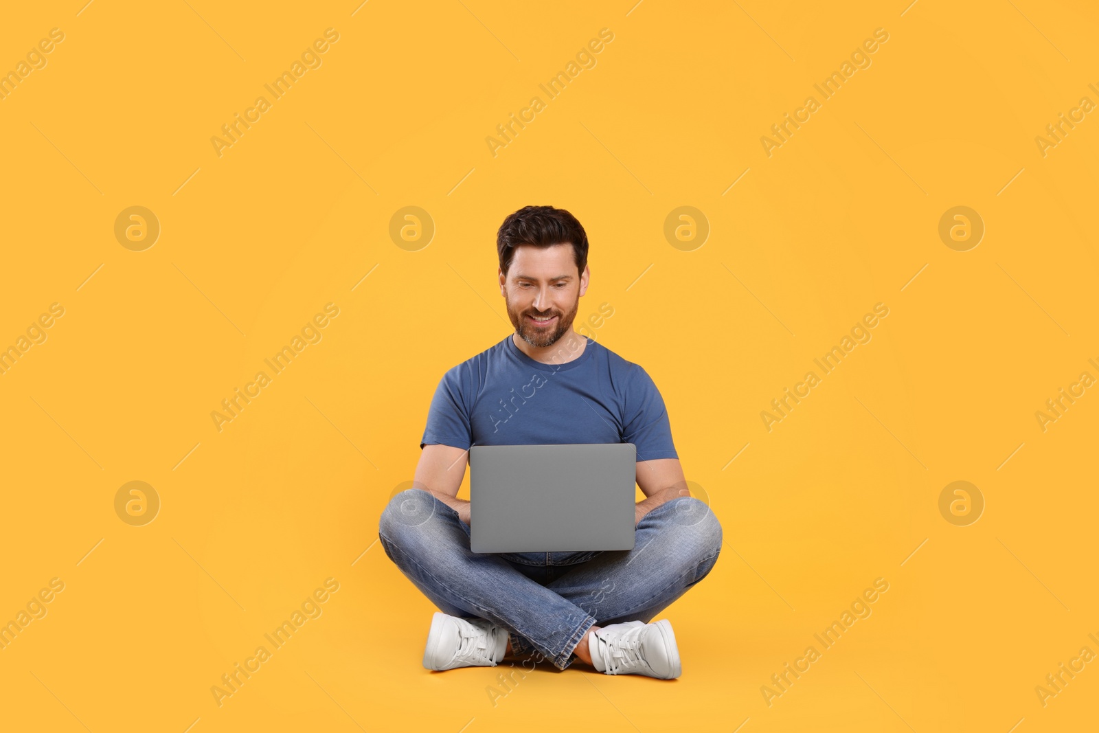 Photo of Happy man with laptop on yellow background