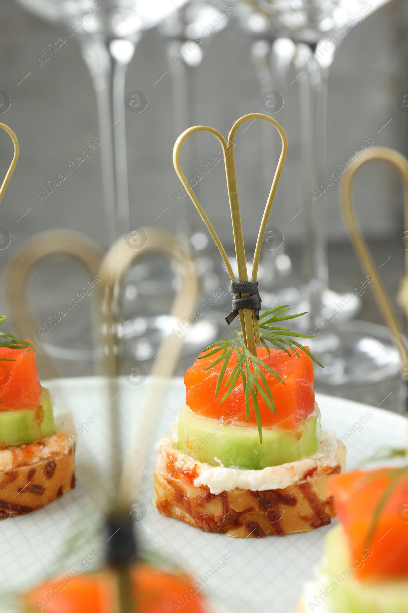 Photo of Tasty canapes with salmon, cucumber, bread and cream cheese on table, closeup